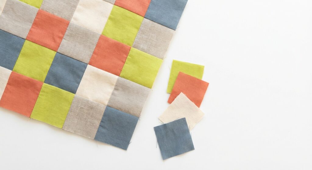 Patchwork-Panel aus bunten Stoffquadraten in Craftery-Farben auf weißem Hintergrund