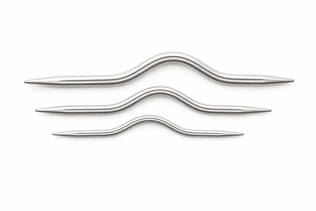 Drei Zopfnadeln in Wellenform in verschiedenen Größen auf weißem Hintergrund
