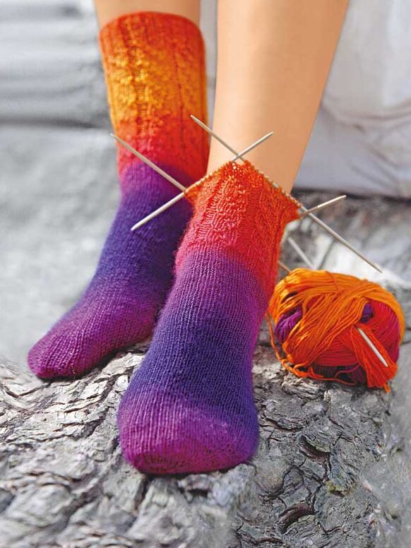 Selbstgemachte Socken in lebhaftem Rot-Orange-Lila-Verlauf. DIY, handgestrickt, warmes Farbspiel.